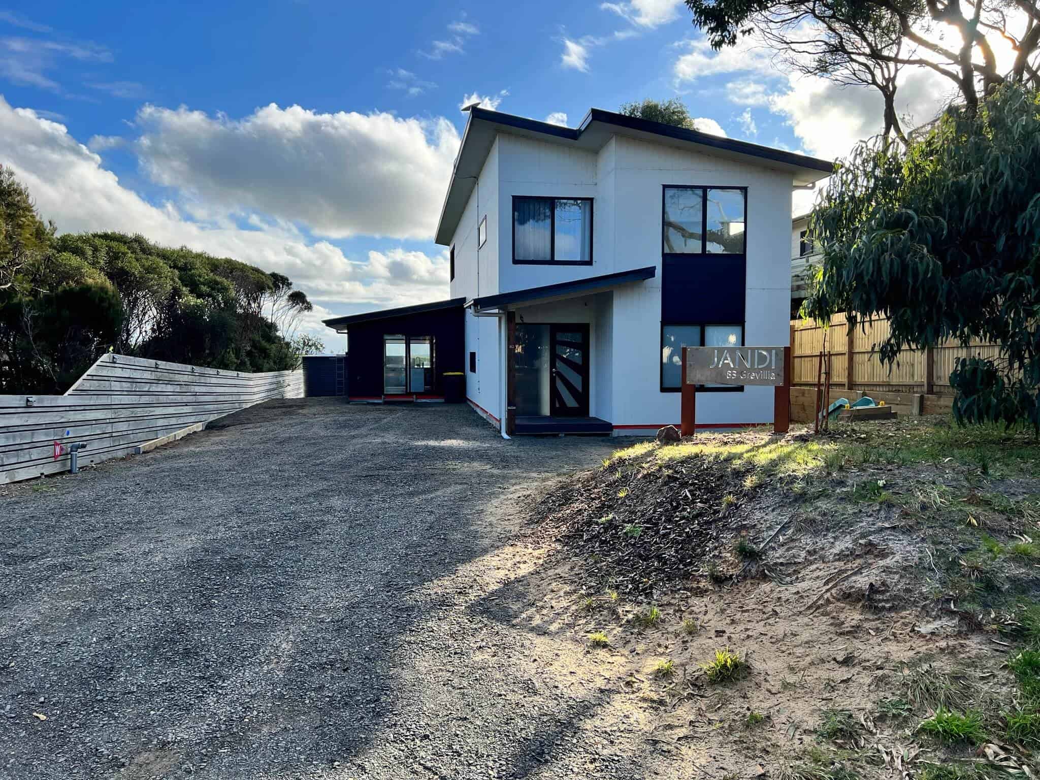 Front of house from street with identifying sign and driveway